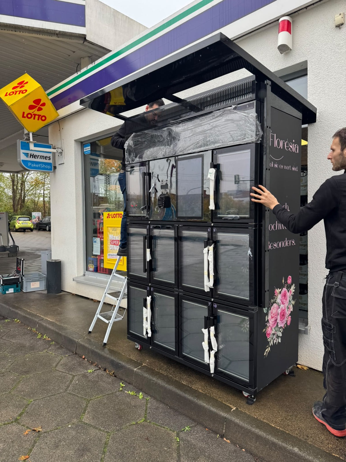 Florésia-Team stellt den Outdoor-Blumenautomaten an der Tankstelle in Fulda auf